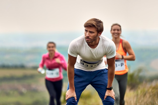 Homme athlétique épuisé prenant une pause après une course de marathon dans la nature