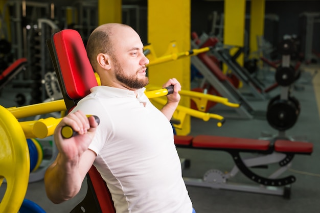 Homme athlétique faisant des séances d'entraînement avec machine d'exercice électrique dans un club de gym