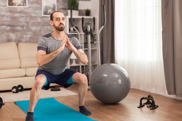 Homme athlétique faisant des squats pour les jambes pendant l'auto-isolement.