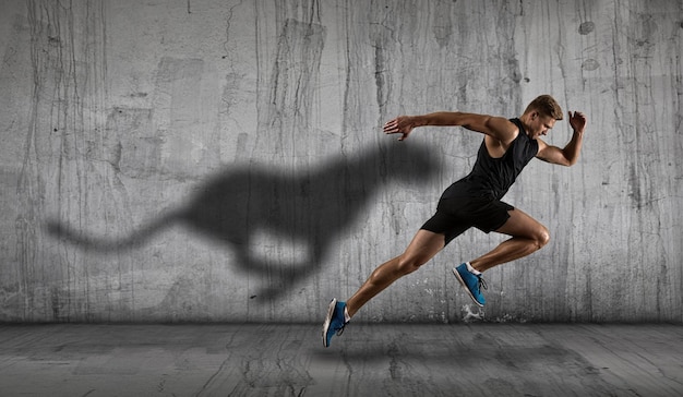 Homme athlétique fort sprinteur courant sur un fond mural sombre portant des vêtements de sport Sport et fitness