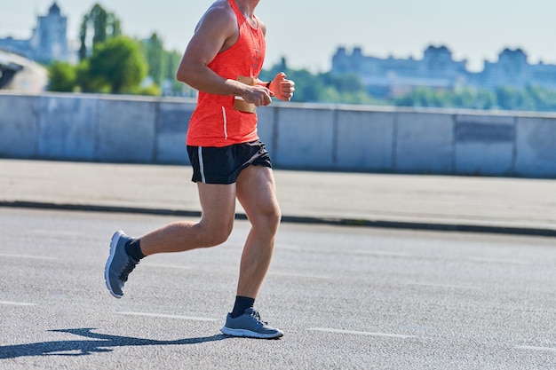 Homme athlétique jogging en tenue de sport sur route de la ville
