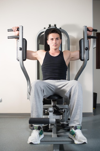 L'homme athlétique pompé est engagé dans l'équipement d'exercice dans la salle de gym