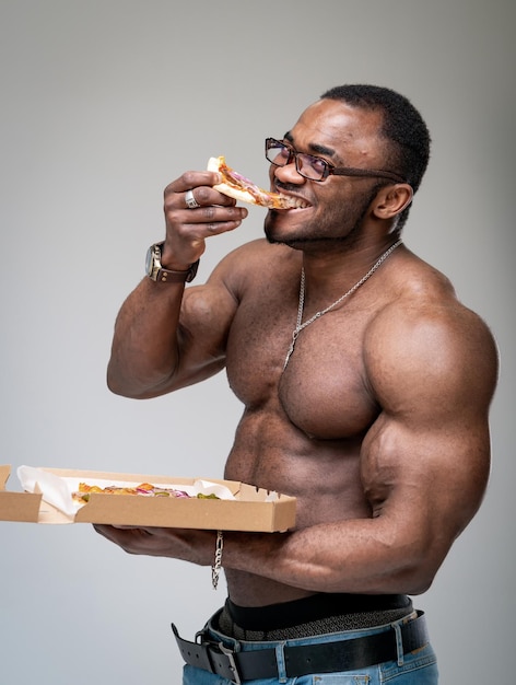 Homme athlétique de remise en forme mangeant de délicieuses pizzas. Heureux mâle musclé profiter de la dégustation de pizza.