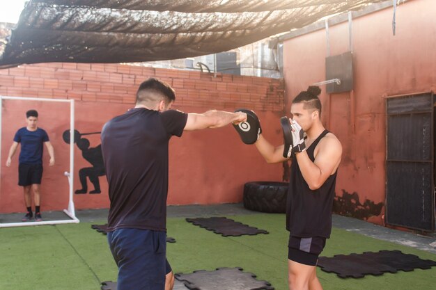 Homme athlétique s'entraînant à la boxe avec son entraîneur.