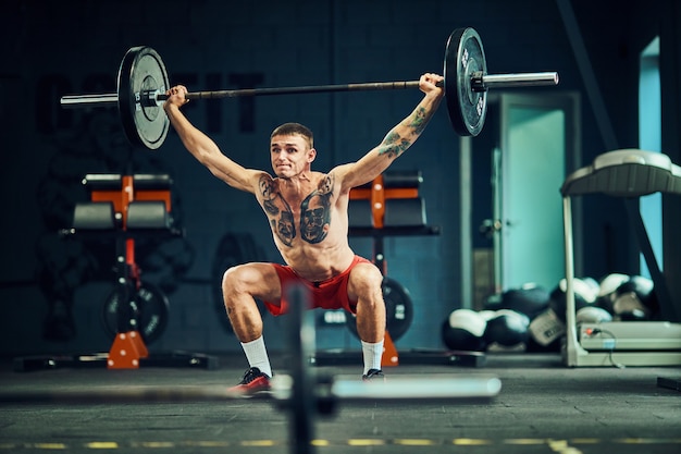 L'homme athlétique s'entraîne au gymnase avec une barre