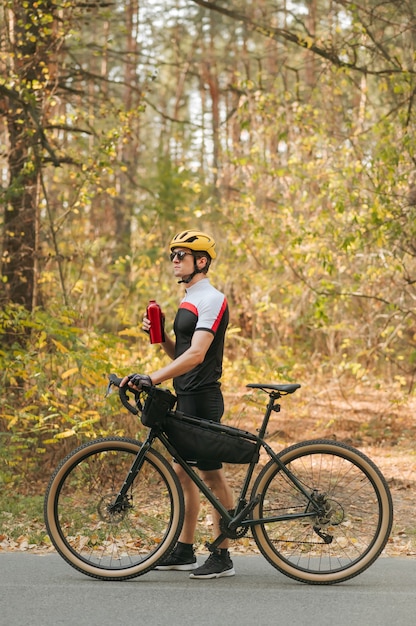 Homme athlétique se dresse sur la route avec un vélo