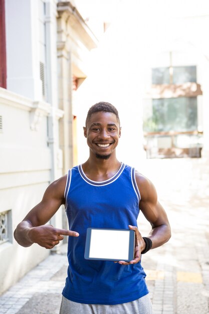 Homme athlétique souriant à l&#39;aide de la tablette tactile