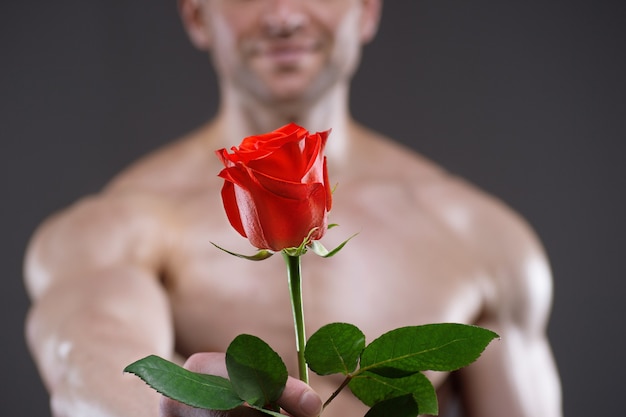 Homme athlétique tenant une rose rouge à la main. Concept de relations amoureuses et romantiques