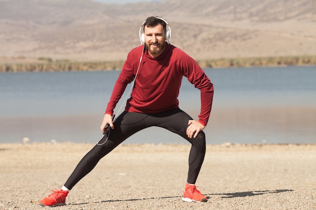 Homme athlétique en tenue de sport qui s'étend dans la nature