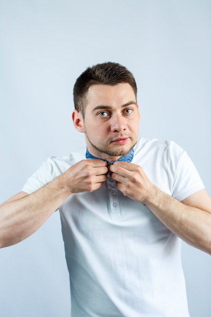 Un homme attache un bouton sur son polo blanc