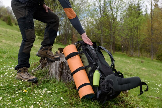 Un homme atteint pour un sac à dos qui repose sur le reste de l'herbe