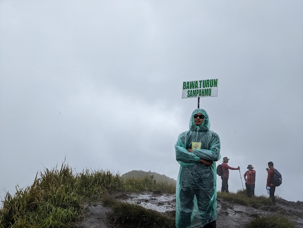 L'homme atteint le sommet de la montagne quand un jour de pluie avec des vibrations brumeuses