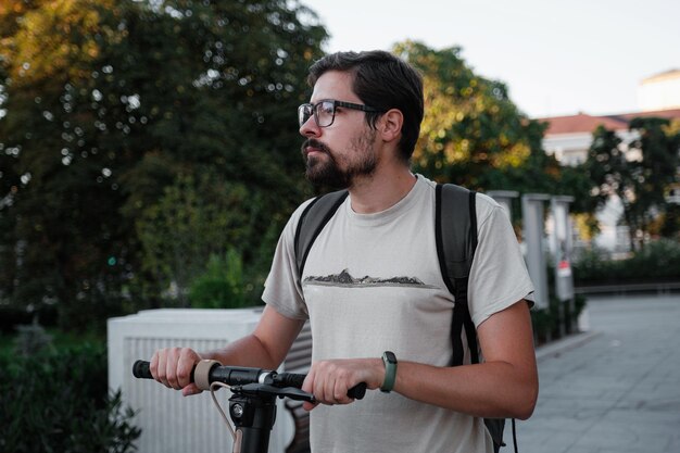 Homme attirant chevauchant un scooter de coup au fond de paysage urbain