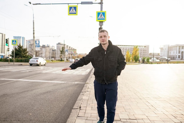 Un homme attrapant une voiture de taxi dans la ville debout près de l'autoroute