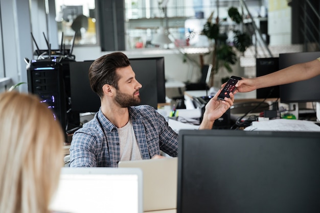 Homme au bureau coworking regardant téléphone mobile.