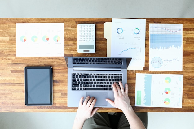 L'homme au bureau entre les données du rapport dans un ordinateur portable