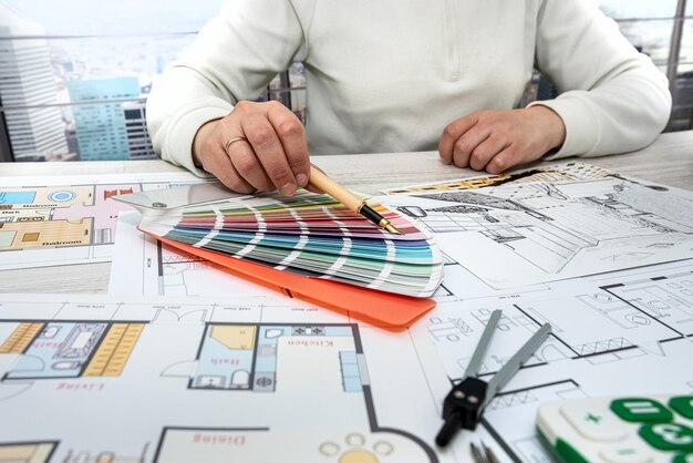 Homme au bureau sélectionne une palette de couleurs pour les dessins de la maison sur le projet