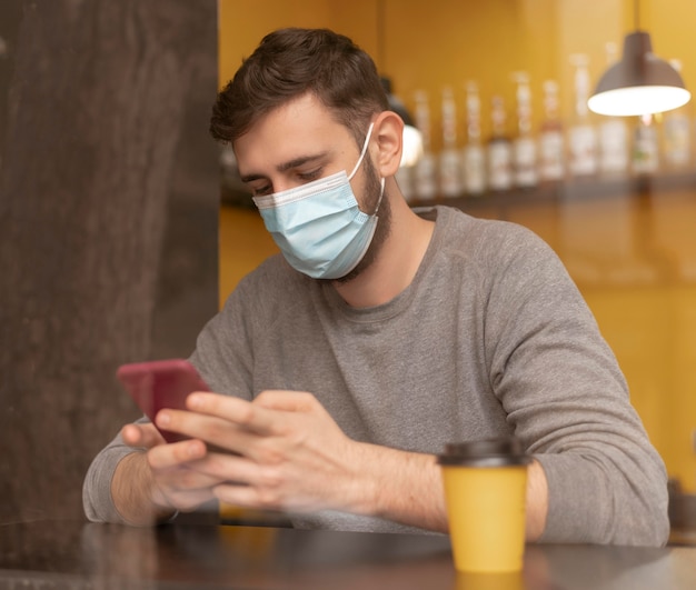 Homme au café portant un masque médical