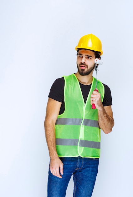 Homme au casque jaune tenant un rouleau de finition et pensant.