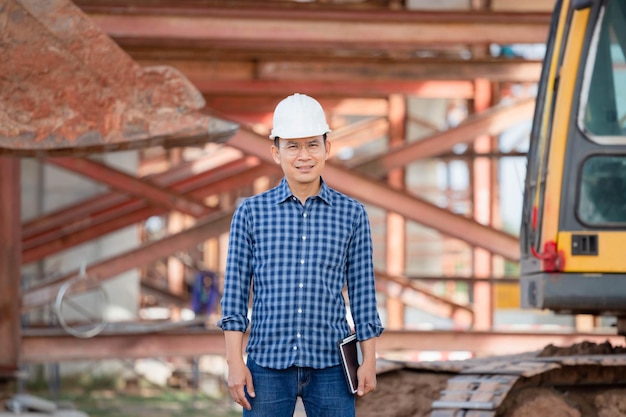 Homme au casque avec tablette numérique sur le chantier de construction d'infrastructures Ingénieur vérifiant le projet sur le chantier