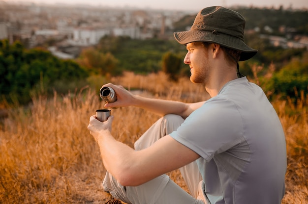 Un homme au chapeau assis sur la colline et se reposant