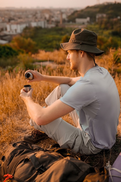 Un homme au chapeau assis sur la colline et se reposant