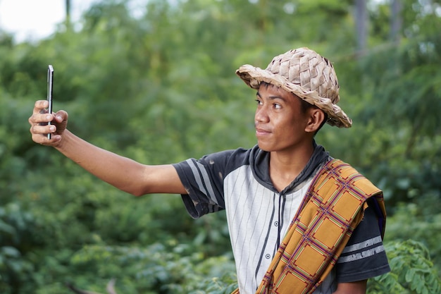 Un homme au chapeau de paille pointe vers un arbre.