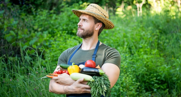 L'homme au chapeau de paille tient l'agro-alimentaire de légumes mûrs frais