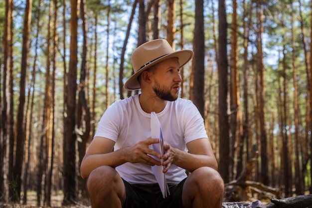 L'homme au chapeau tient une carte dans ses mains lors d'un voyage de camping. Randonnée en montagne, forêt.