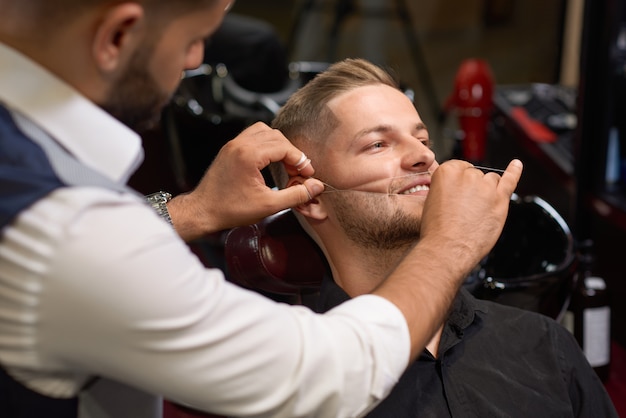 Homme au cours de la procédure d'enfilage de la barbe dans un salon de coiffure