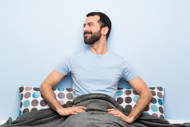 Homme au lit posant avec les bras à la hanche et souriant