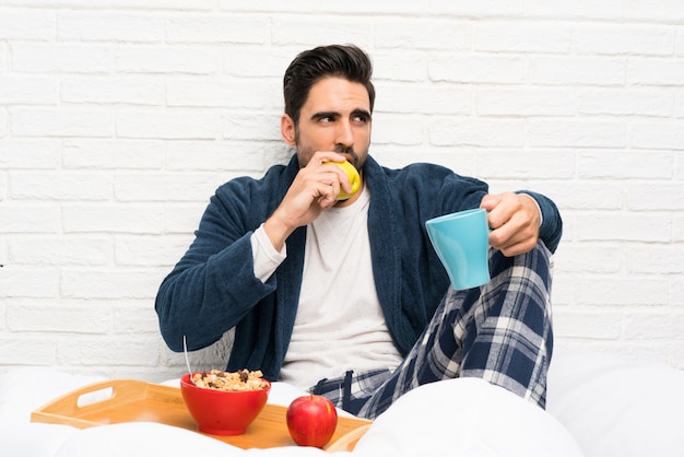 Homme au lit avec robe de chambre et petit déjeuner