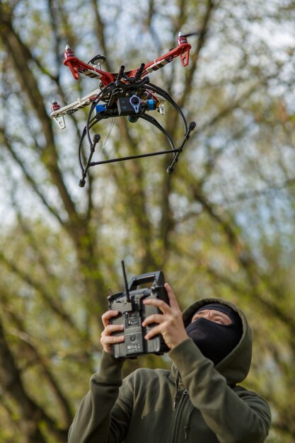 Homme au masque actionnant un drone avec télécommande