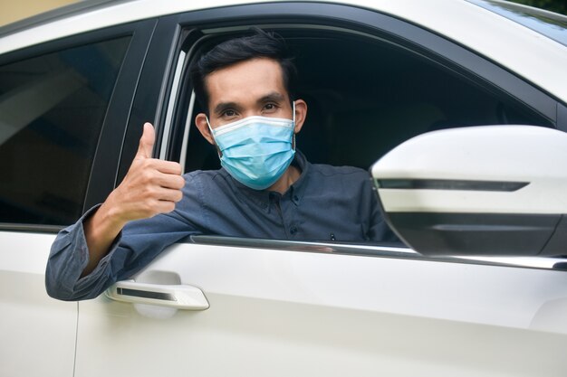 Homme au masque facial assis dans une voiture