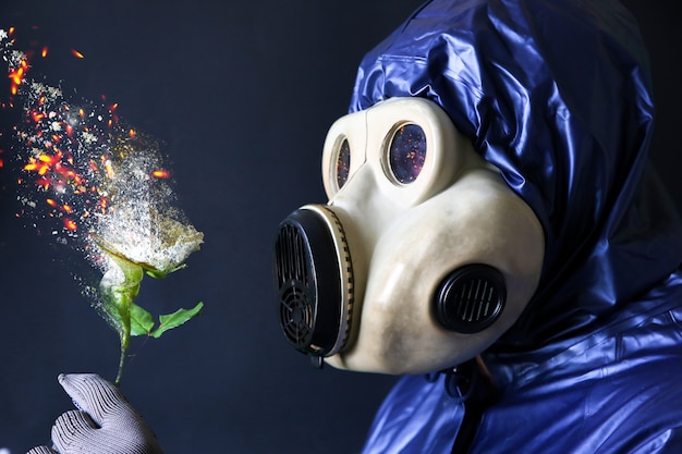 Homme au masque à gaz tenant une fleur en feu. Influence du rayonnement. Pollution environnementale. Notion de Tchernobyl. Une énergie nucléaire dangereuse.