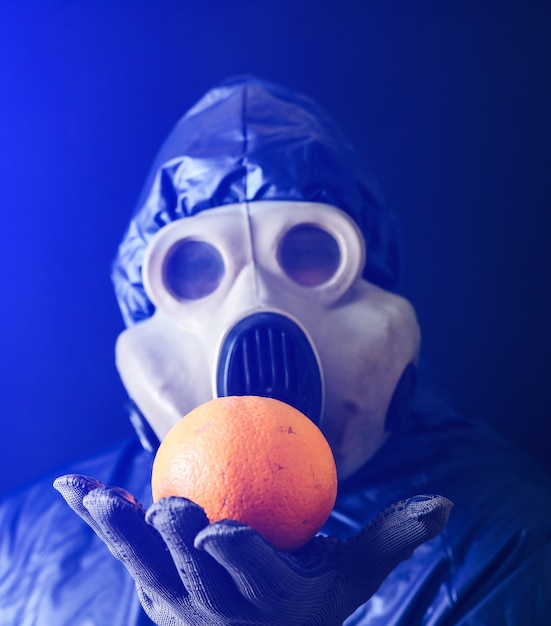 Homme au masque à gaz tenant orange. Influence du rayonnement. Pollution environnementale. Notion de Tchernobyl. Une énergie nucléaire dangereuse. Désastre écologique.