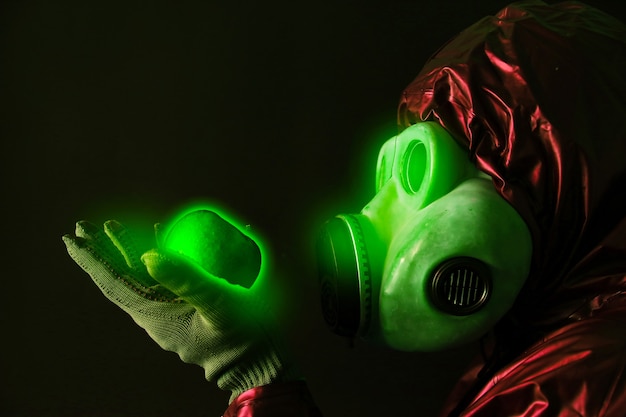 Homme au masque à gaz tenant une pomme lumineuse radioactive. Influence du rayonnement. Pollution environnementale. Notion de Tchernobyl. Une énergie nucléaire dangereuse.