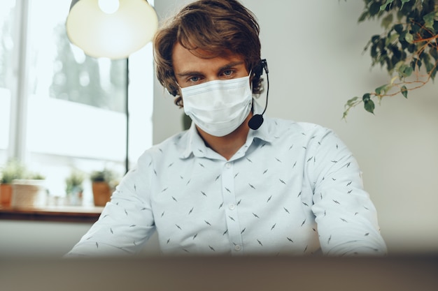 Homme au masque médical travaillant à domicile pendant la quarantaine du coronavirus