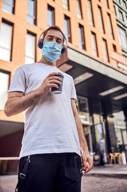 L'homme au masque se tient avec du café