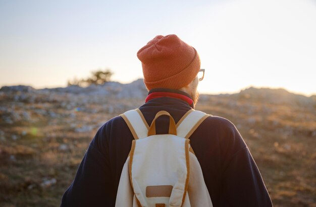 Un homme au sommet d'une falaise dans les montagnes printanières au coucher du soleil et profitant de la vue sur la nature