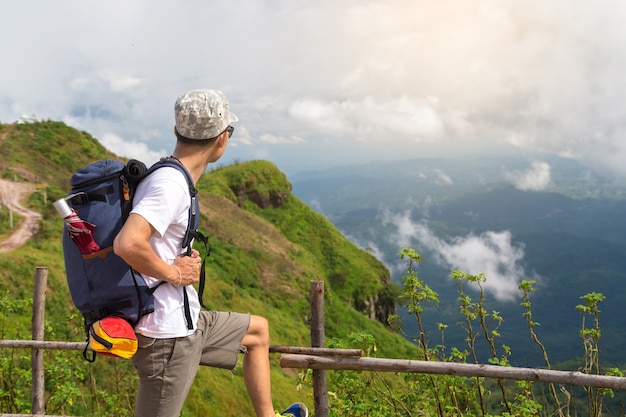 Homme au sommet de la montagne debout sur le rocher en regardant une vue sur la montagne.