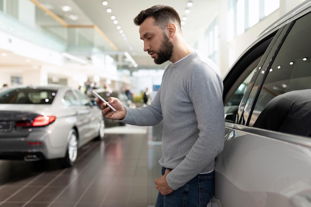 Un homme au téléphone étudie les caractéristiques d'un suv chez un concessionnaire automobile