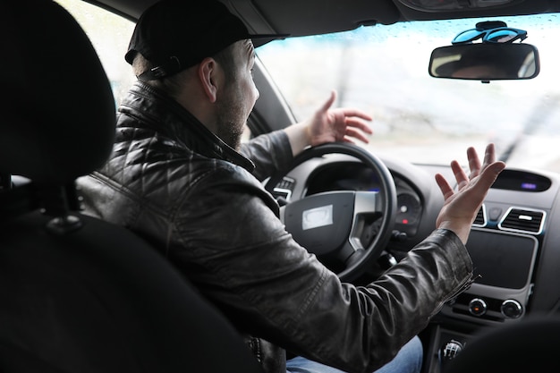 L'homme au volant d'une voiture en conduisant un jour de pluie