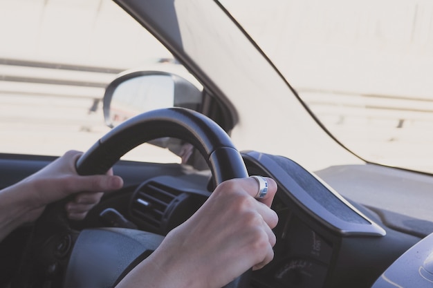 L'homme au volant d'une voiture. Mains féminines sur le volant d'une voiture pendant la conduite.