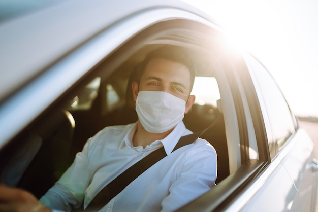 Un homme au volant d'une voiture met un masque médical lors d'une épidémie dans une ville en quarantaine.