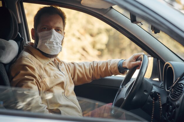 Un homme au volant d'une voiture met un masque médical lors d'une épidémie
