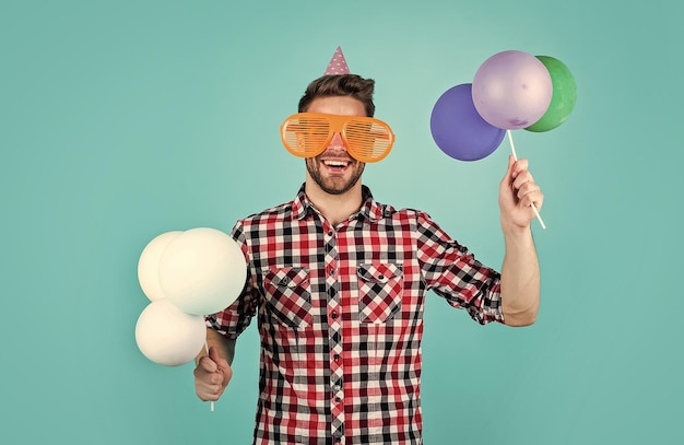 Un homme aux cheveux et à la barbe soignés à la mode tient une fête de ballons