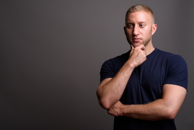 Homme aux cheveux blonds sur mur gris