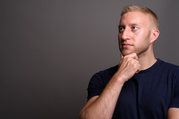 Homme aux cheveux blonds sur mur gris