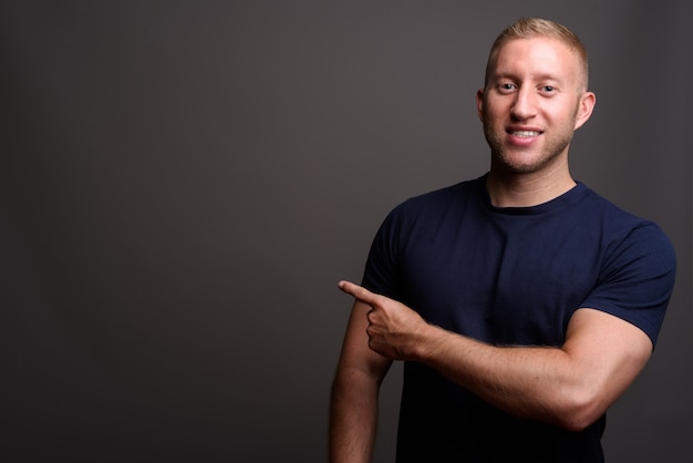 Homme aux cheveux blonds sur mur gris